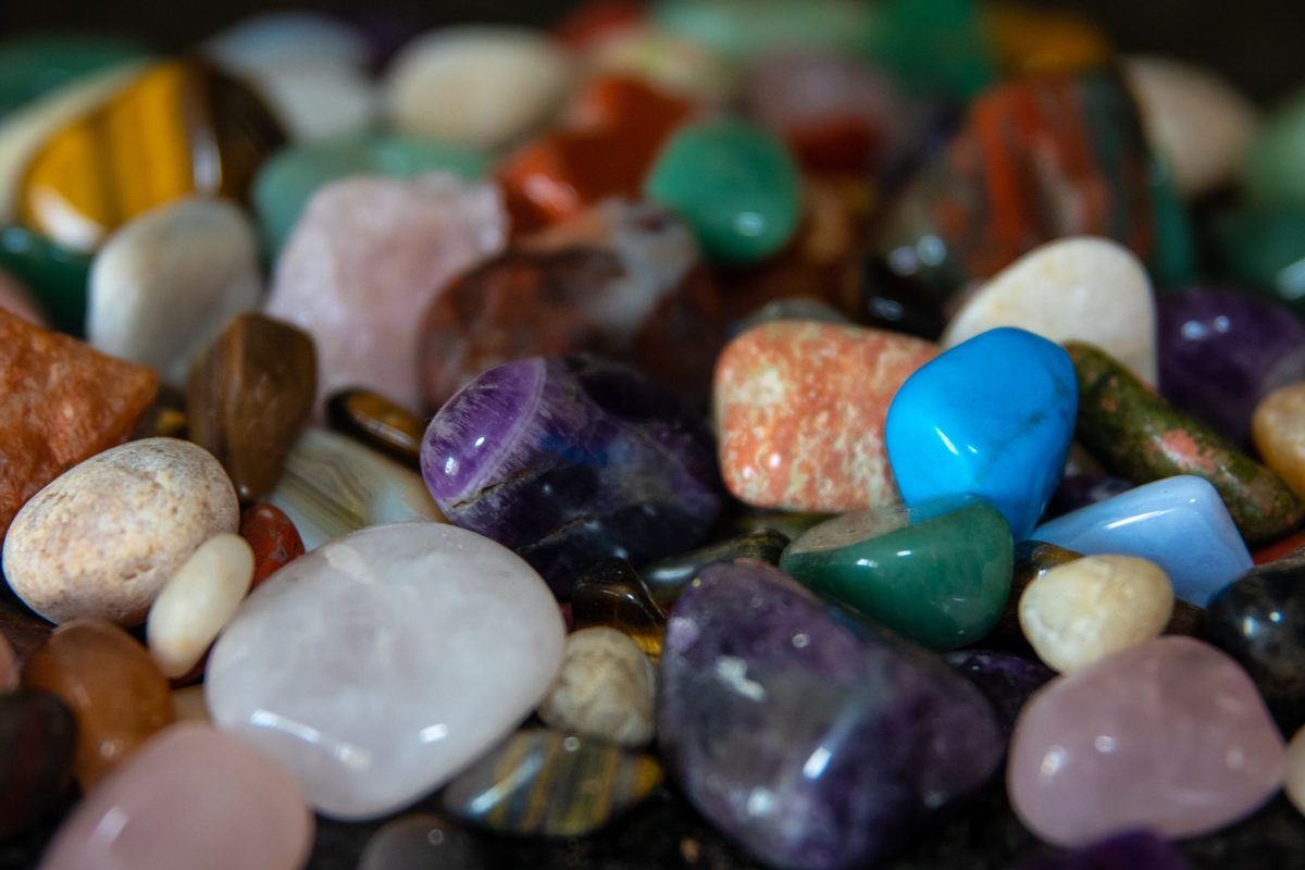Close-up of assorted tumbled gemstones in purple, green, blue, pink, and amber