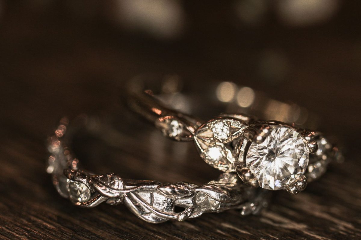 Round brilliant solitaire engagement ring and diamond band on dark wood