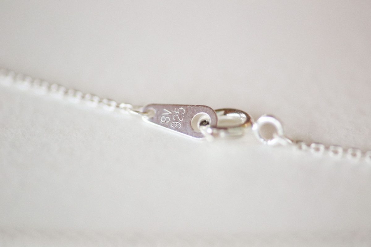 Close-up of a tarnished silver chain necklace on a neutral surface